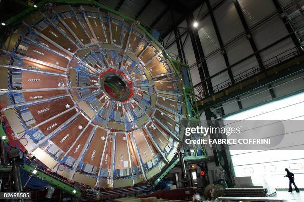 Woman passes on March 22, 2007 near Geneva, behind a layers of the world's largest superconducting solenoid magnet , one of the experiments preparing...