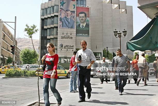 Syrians walk past a building bearing posters of Syrian President Bashar al-Assad in Damascus on June 22, 2008. Senior UN atomic experts were set to...