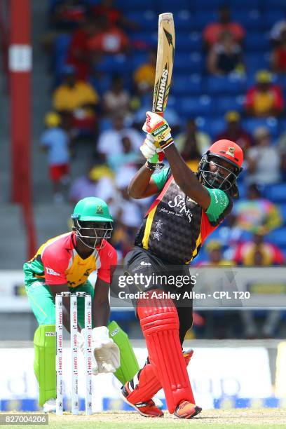 In this handout image provided by CPL T20,Chris Gayle of St Kitts and Nevis Patriots hits six en route to 66 as Chadwick Walton looks on during Match...