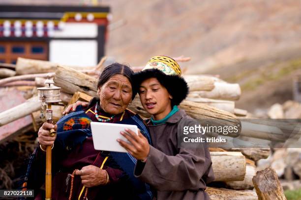 jeune garçon avec grand-mère à l’aide de tablette numérique - distrikt leh photos et images de collection