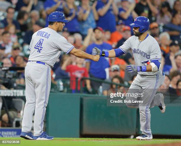 Jose Bautista of the Toronto Blue Jays receives congratulations from third base coach Luis Rivera after hitting two run home run in the third inning...