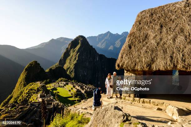 tourists being photographed overlooking machu picchu. - ogphoto stock pictures, royalty-free photos & images