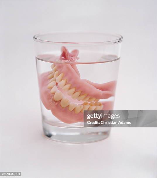 false teeth in glass of water, close-up - dentures stock pictures, royalty-free photos & images