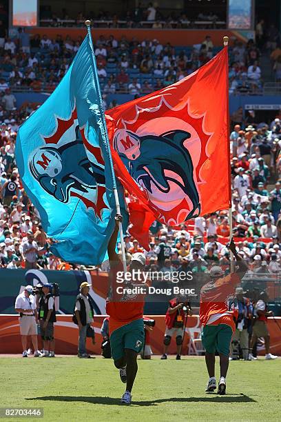 Flag bearers run with giant flags with the logo of the Miami Dolphins on them against the New York Jets at Dolphin Stadium on September 7, 2008 in...