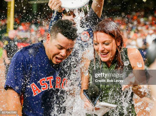 Juan Centeno of the Houston Astros and AT&T SportsNet sideline reporter Julia Morales are doused with water from Collin McHugh during a post game...