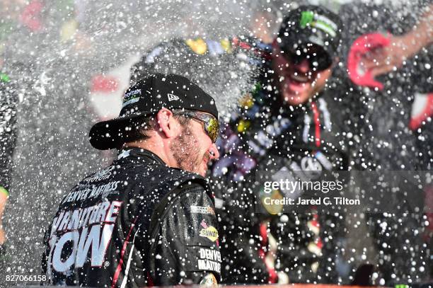 Martin Truex Jr., driver of the Furniture Row/Denver Mattress Toyota, celebrates by spraying champagne in Victory Lane after winning the Monster...