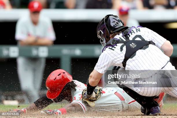 Odubel Herrera of the Philadelphia Phillies is tagged out at the plate by Ryan Hannigan of the Colorado Rockies after trying to score on a Hyun Soo...