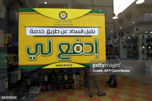 Picture taken on July 24, 2017 shows a poster of the "Edfali" mobile phone app on the window of a store that accepts electronic payment systems, in...