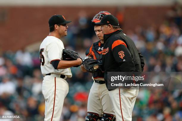 Starting pitcher Matt Moore of the San Francisco Giants talks to catcher Buster Posey and Pitching Coach Dave Righetti in the second inning against...