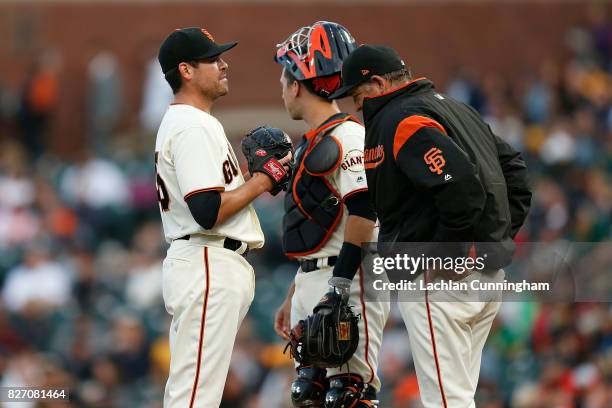 Starting pitcher Matt Moore of the San Francisco Giants talks to catcher Buster Posey and Pitching Coach Dave Righetti in the second inning against...