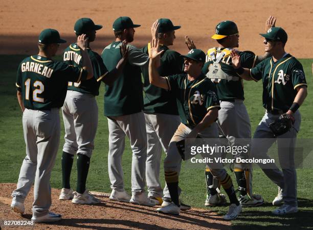 Jaycob Brugman, third from right, Mark Canha, far right, and their Oakland Athletics teammate celebrate after their 11-10 win over the Los Angeles...