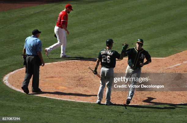 Ryon Healy of the Oakland Athletics gets a high-five from teammate Matt Chapman after scoring on a single to right field by teammate Chad Pinder off...
