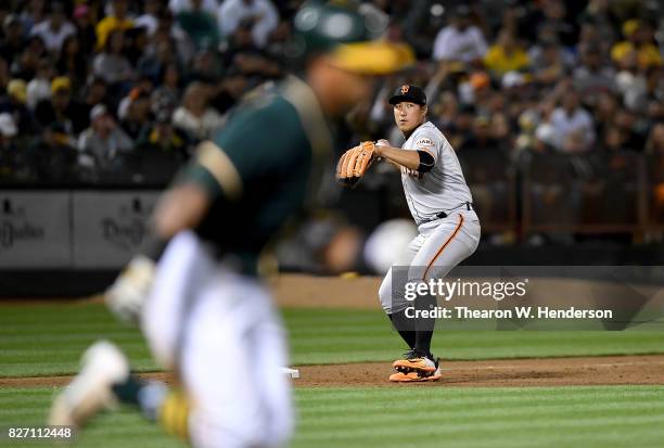 Jae-Gyun Hwang of the San Francisco Giants looks to throw to first base to throw out Khris Davis of the Oakland Athletics in the bottom of the fifth...