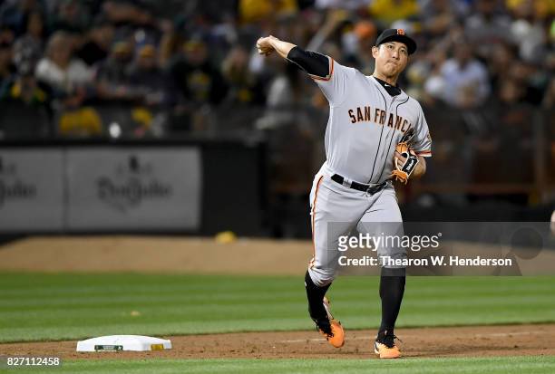 Jae-Gyun Hwang of the San Francisco Giants looks to throw to first base to throw out Khris Davis of the Oakland Athletics in the bottom of the fifth...