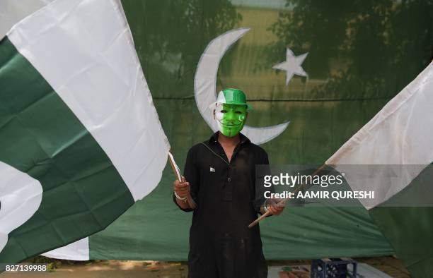 Pakistani vendor holds national flags as he waits for customers ahead of Independence Day celebrations in Islamabad on August 7, 2017. - Pakistan...