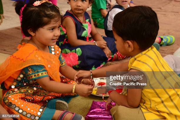 Rajasthani children tie 'rakhi' on the wrist of a male classmate in celebration of Raksha Bandhan in India.