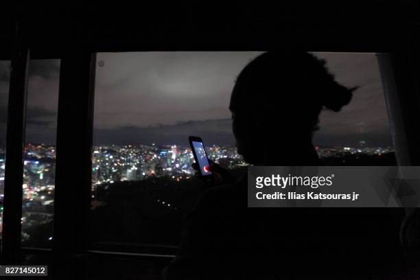 silhouette of girl with smartphone in hand, city lights in the background - car display background stock-fotos und bilder