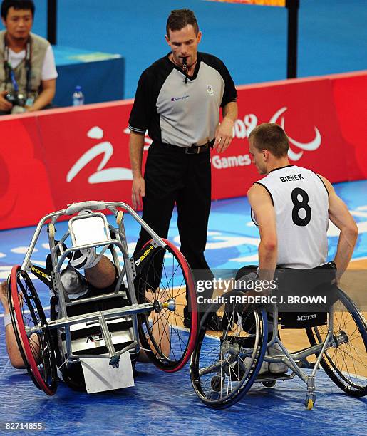 Germany's Andre Bienek and referee Sergio Giordano of Canada look on as Japan's Reo Fujimoto tumbles to the ground in their men's wheelchair...