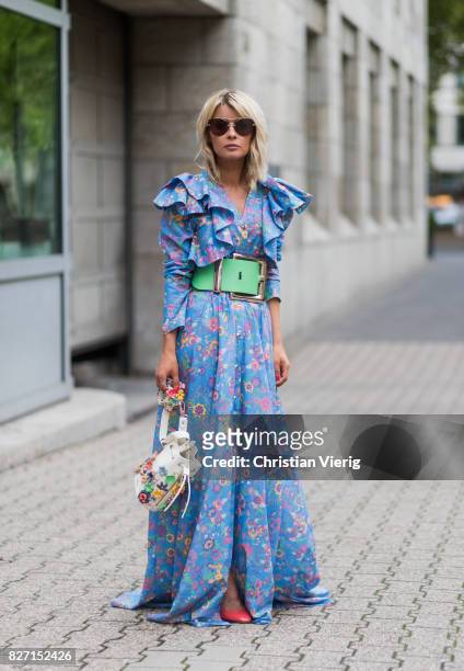 Model and fashion blogger Gitta Banko wearing a floral-patterned dress and a pastel-green oversize waist belt by Marina Hoermanseder, a Kasper...