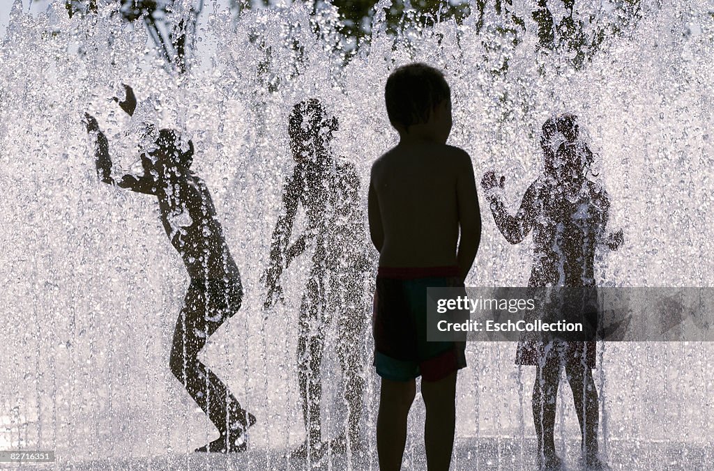 Silhouettes of children playing in fountain