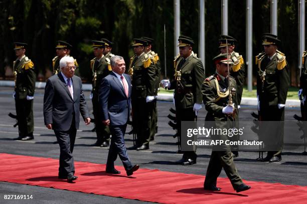 Jordan's King Abdullah II and Palestinian president Mahmud Abbas observe the honor guard during a visit in the West Bank city of Ramallah on August...