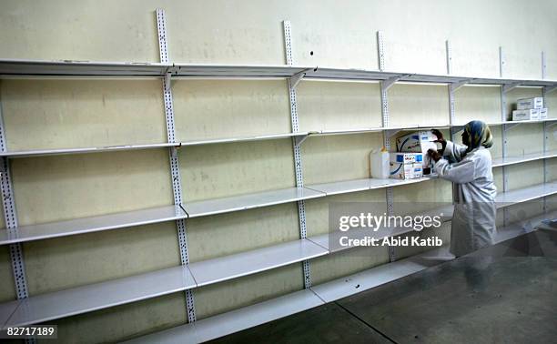 Worker stands next to empty shelves at the Middle East Company for Pharmaceutical Industries September 08, 2008 in Bait Hanoun, Gaza Strip....