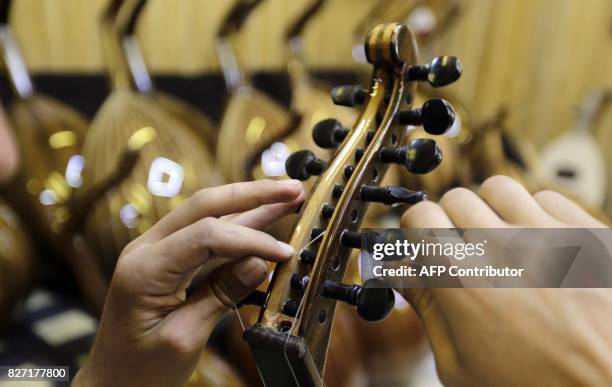 Ali Khalifeh, a lute-maker, adjusts the strings on a oud at a shop in the Syrian capital Damascus on July 17, 2017. The first Damascene oud was...