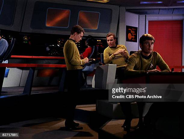 Canadian actor William Shatner sits on the bridge of the USS Enterprise and speaks with an unidentified actor while a second unidentified actor sits...