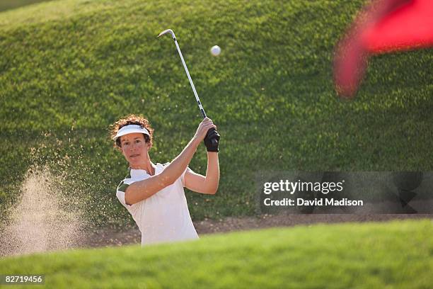 woman golfer hitting out of bunker or sand trap. - female golf stockfoto's en -beelden