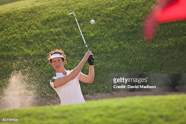 woman golfer hitting out of bunker or sand trap. - golf short iron stock pictures, royalty-free photos & images