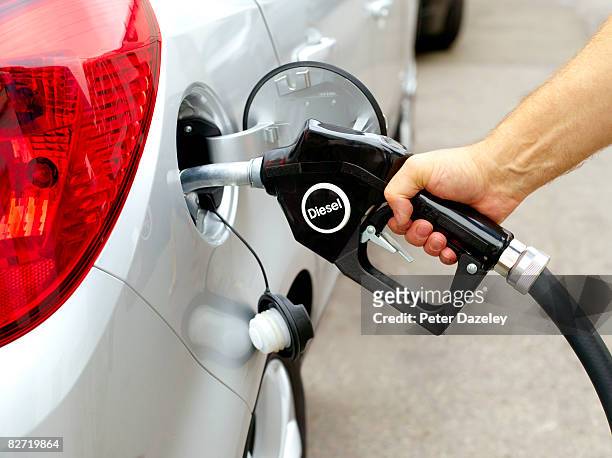 man filling car with diesel pump - diesel stockfoto's en -beelden