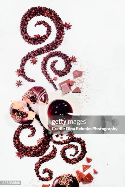 coffee grains lying in the shape of a swirl with the cup, cinnamon, anise stars, chocoalte and donuts - chocolate swirl from above stock pictures, royalty-free photos & images