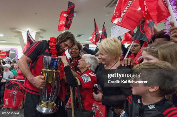 Captain Samuel Whitelock of the Crusaders presents the Super Rugby trophy to 95-year-old fan Doreen Searle during the Crusaders arrival at...