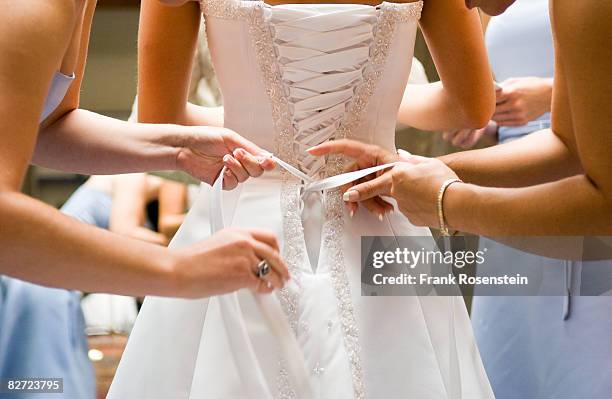 bridesmaids help bride into her dress - wedding dress stockfoto's en -beelden