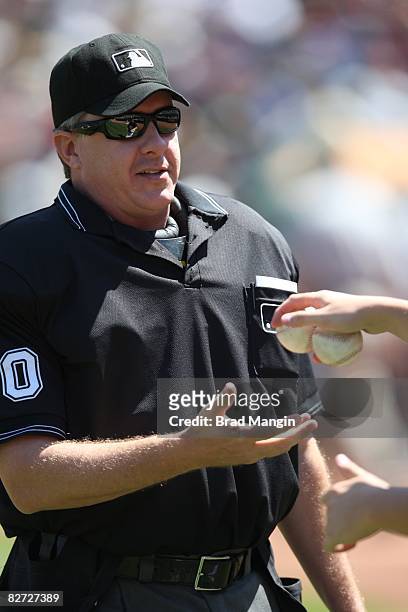 Home-plate umpire Paul Emmel takes fresh baseballs during the game between the Oakland Athletics and the Minnesota Twins at the McAfee Coliseum in...