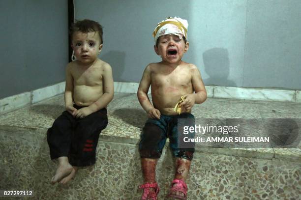 Injured Syrian children cry as they wait to receive treatment at a makeshift hospital in Jobar on August 5 following a reported government airstrike...