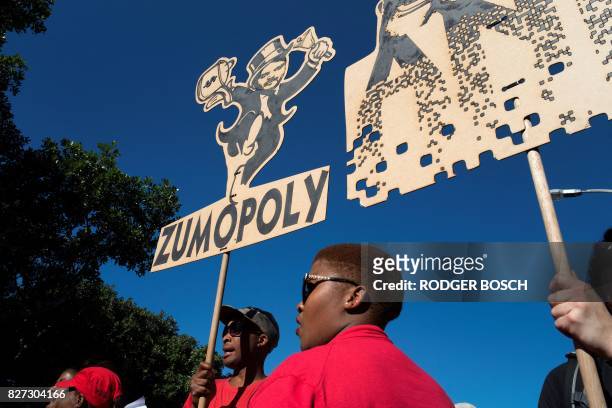 People carry a placard with a parody of one of the Gupta brothers during a demonstration march organised by a broad-based coalition called...