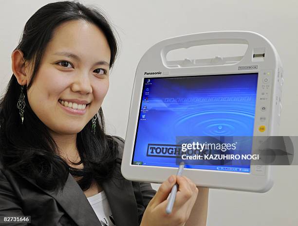 An employee of Japan's electronics giant Matsushita Electric Industrial displays the portable PC "Toughbook" for medical use, equipped with Intel's...