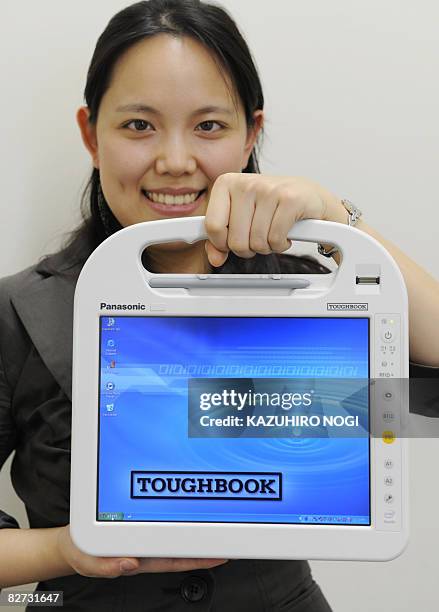 An employee of Japan's electronics giant Matsushita Electric Industrial displays the portable PC "Toughbook" for medical use, equipped with Intel's...