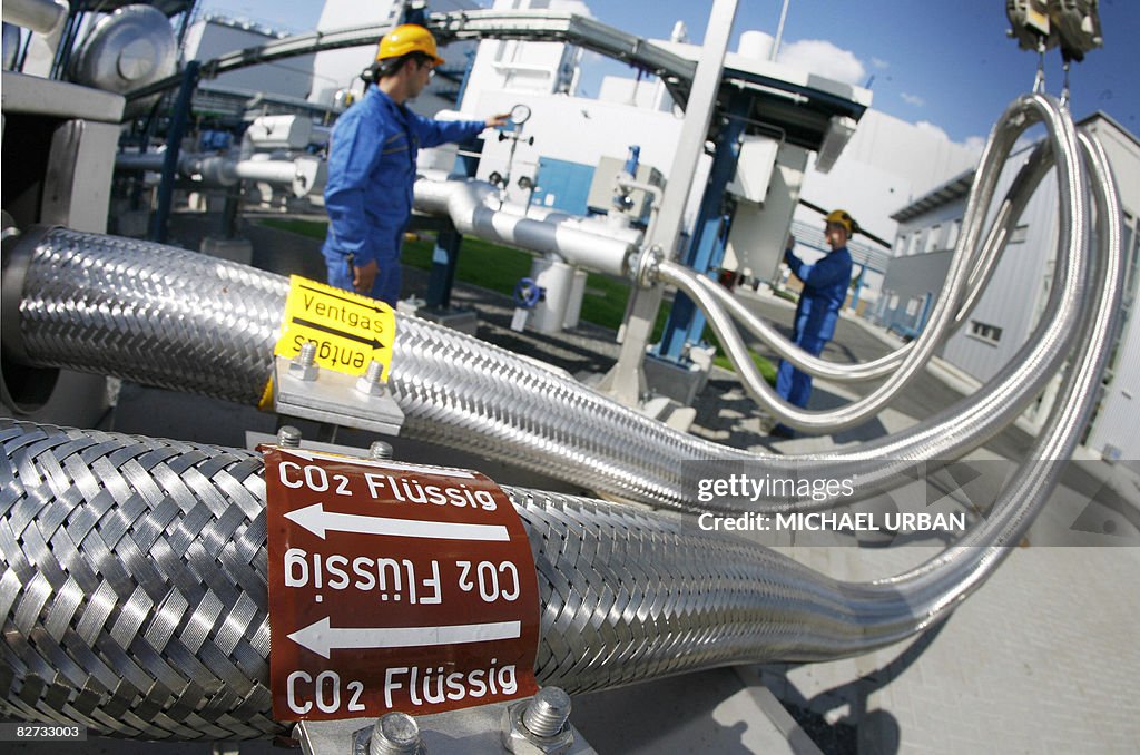 Two employees work on pipes carrying liq