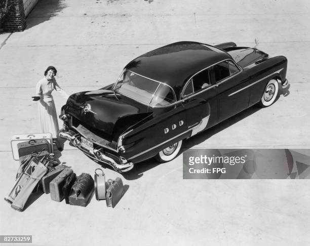 Woman demonstrates the trunk capacity of the 1951 Packard Patrician 400.