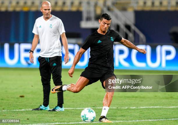 Real Madrid's French head coach Zinedine Zidane looks on as Real Madrid's forward Cristiano Ronaldo shoots the ball during a training session before...