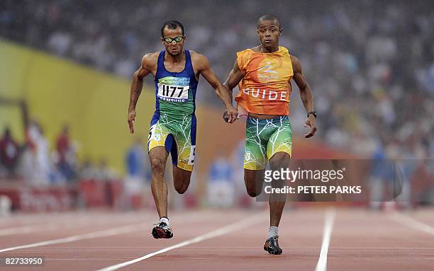 Partially-sighted runner Lucas Prado of Brazil runs with his guide as he wins the A final of the 100m T11 during the 2008 Beijing Paralympic Games at...