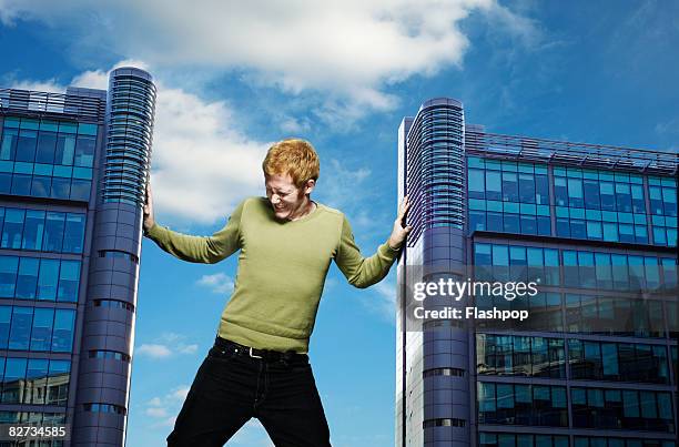 portrait of man pushing against buildings - redhead stock pictures, royalty-free photos & images