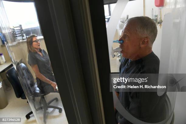 Kathy Kramer, a respiratory therapist, left, asks her patient John Castona, right, to take big deep breathes during a routine pulmonary function test...