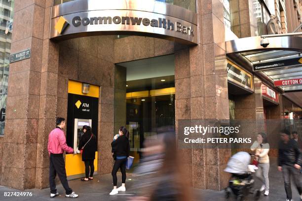 People walk past a Commonwealth Bank branch in the central business district of Sydney on August 8, 2017. - Australia's Commonwealth Bank said on...