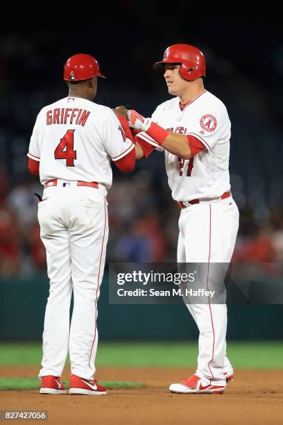 Infield coach Alfredo Griffin congratulates Mike Trout of the Los Angeles Angels of Anaheim after hitting his one thousandth career hit during the...