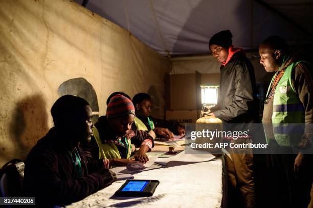 Kenyan Independent Electoral and Boundaries Commission officials verify voters' identity at the start of voting operations for th general elections...