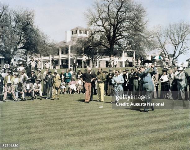 Bobby Jones plays his tee shot on the first hole while Tommy Armour , Walter Hagen , Gene Sarazen watch alongside a gallery of patrons in front of...