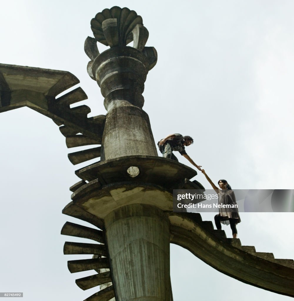 Man leading a woman up a surreal structure